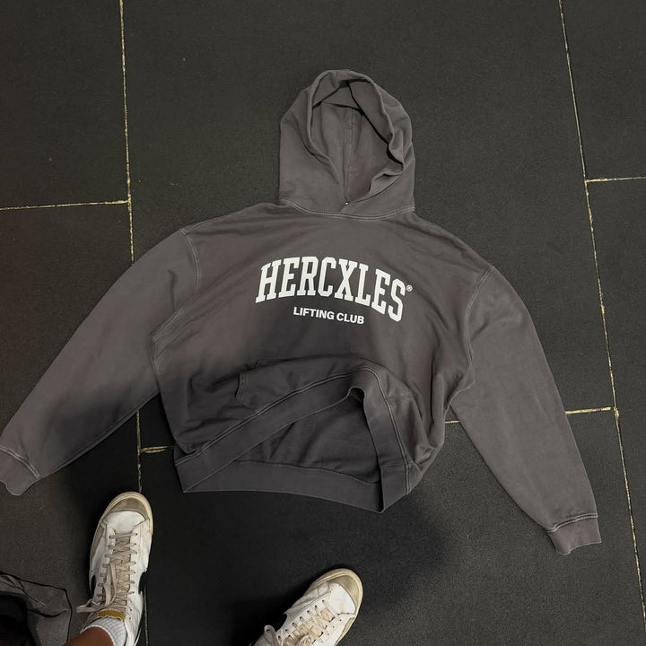 Grey HERCXLES Lifting Club hoodie laid out on a gym floor
