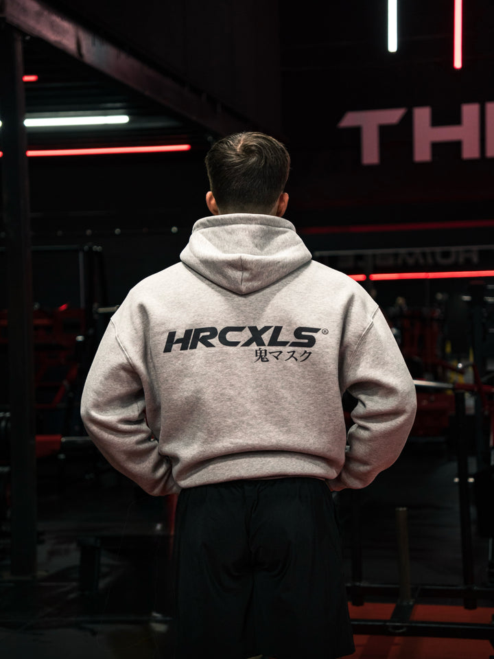 Rear view of an athlete in a grey HRCXLS graphic hoodie under red and white gym lights