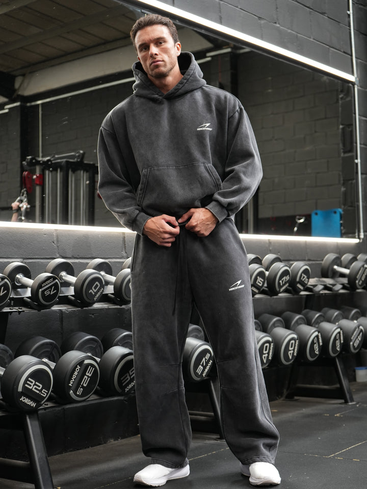 Athlete wearing matching black vintage fleece HERCSTUDIOS oversized hoodie and sweatpants in a gym