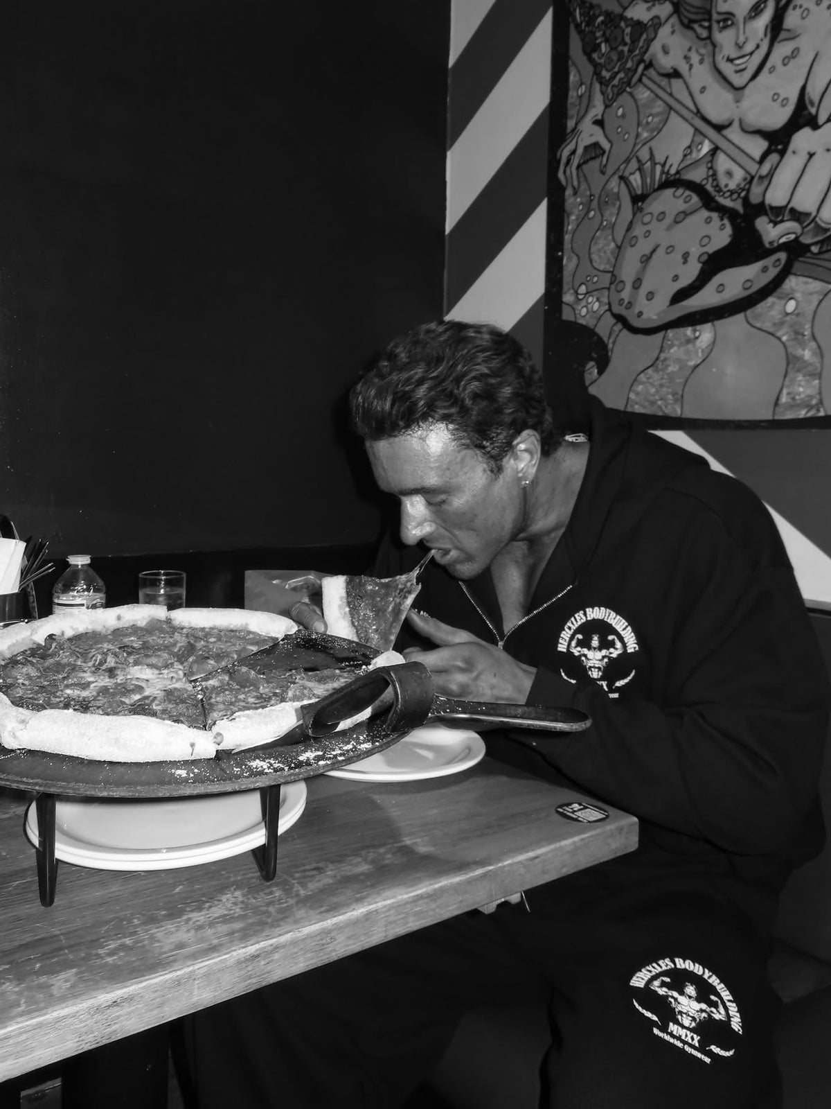 Worldwide Competitor Sweatpants - Black / White model seated in zip hoodie and matching joggers with pizza (p3)