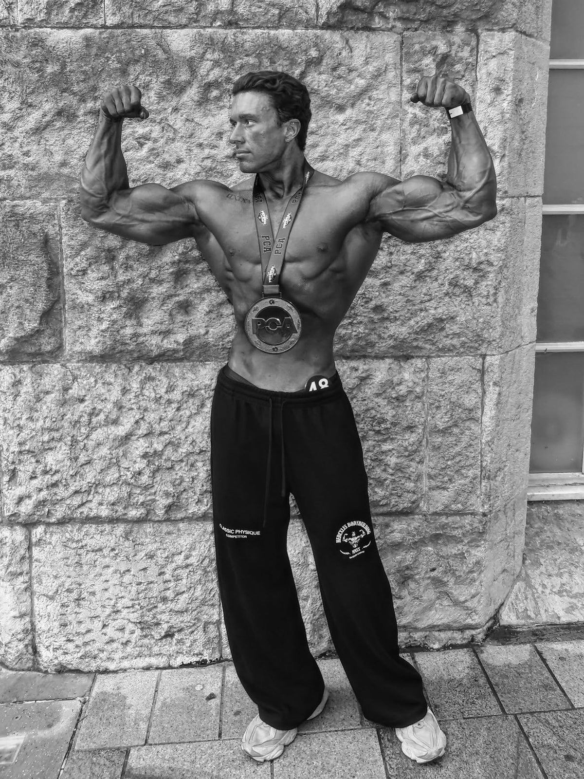 Worldwide Competitor Sweatpants - Black / White model competitor posing in joggers with medal (p7)