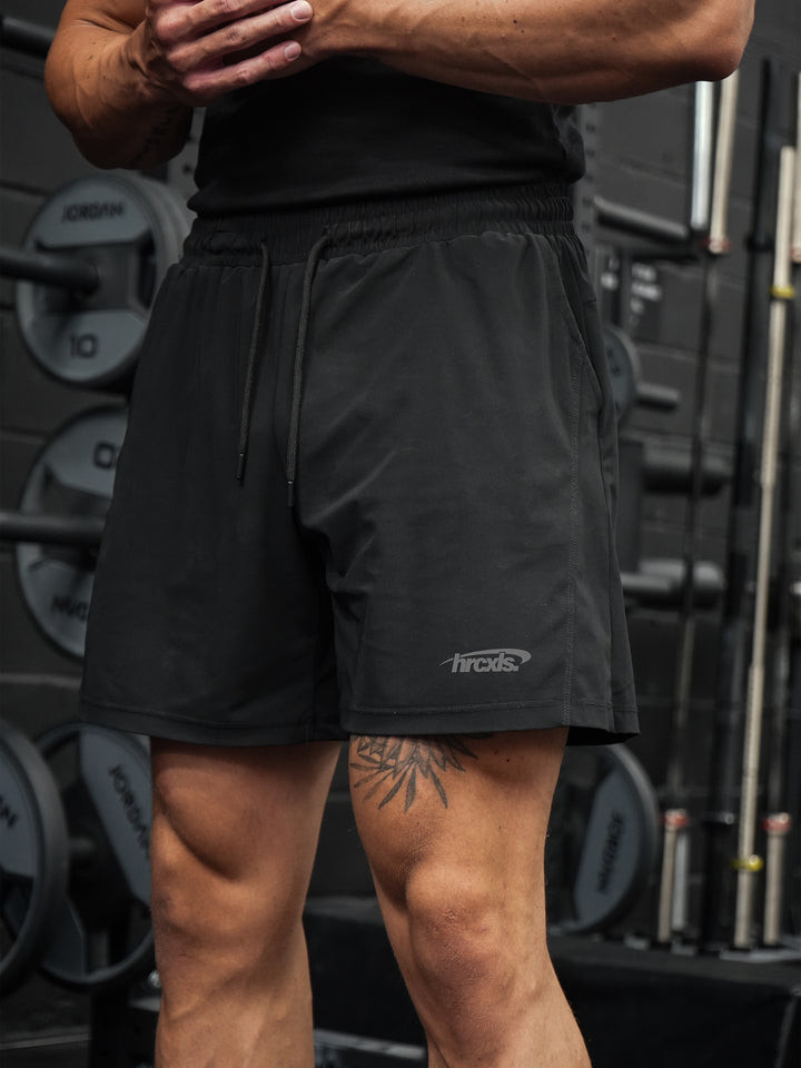 Close-up of black HERCXLES seven-inch training shorts in the gym