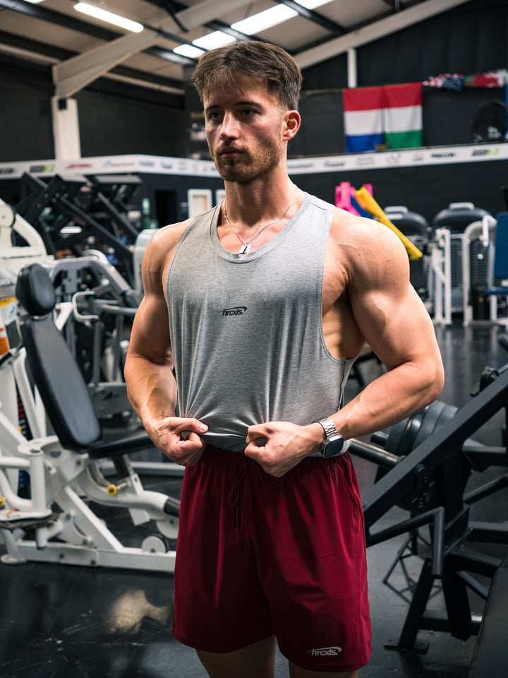 Male athlete wearing a grey HRCXLS vest and burgundy shorts in the gym